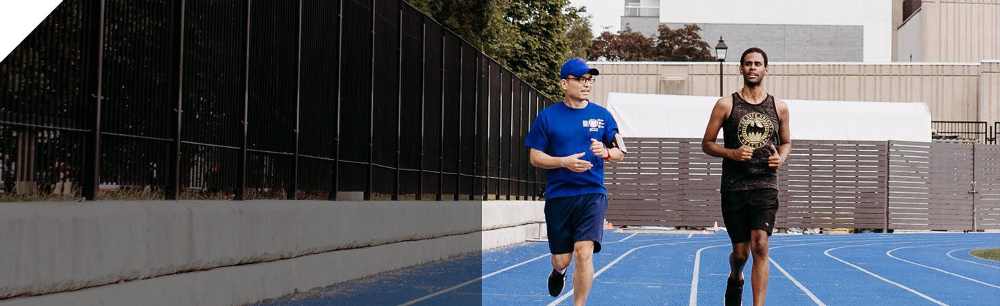 Two men running on a blue running track