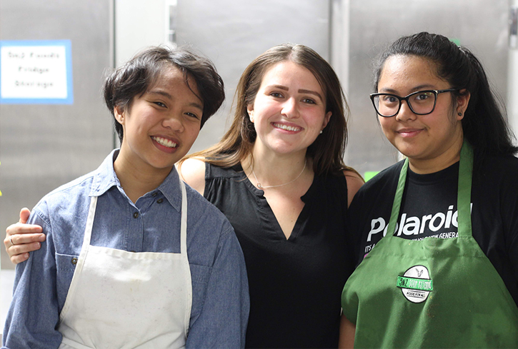 Three volunteers smiling in soup kitchen